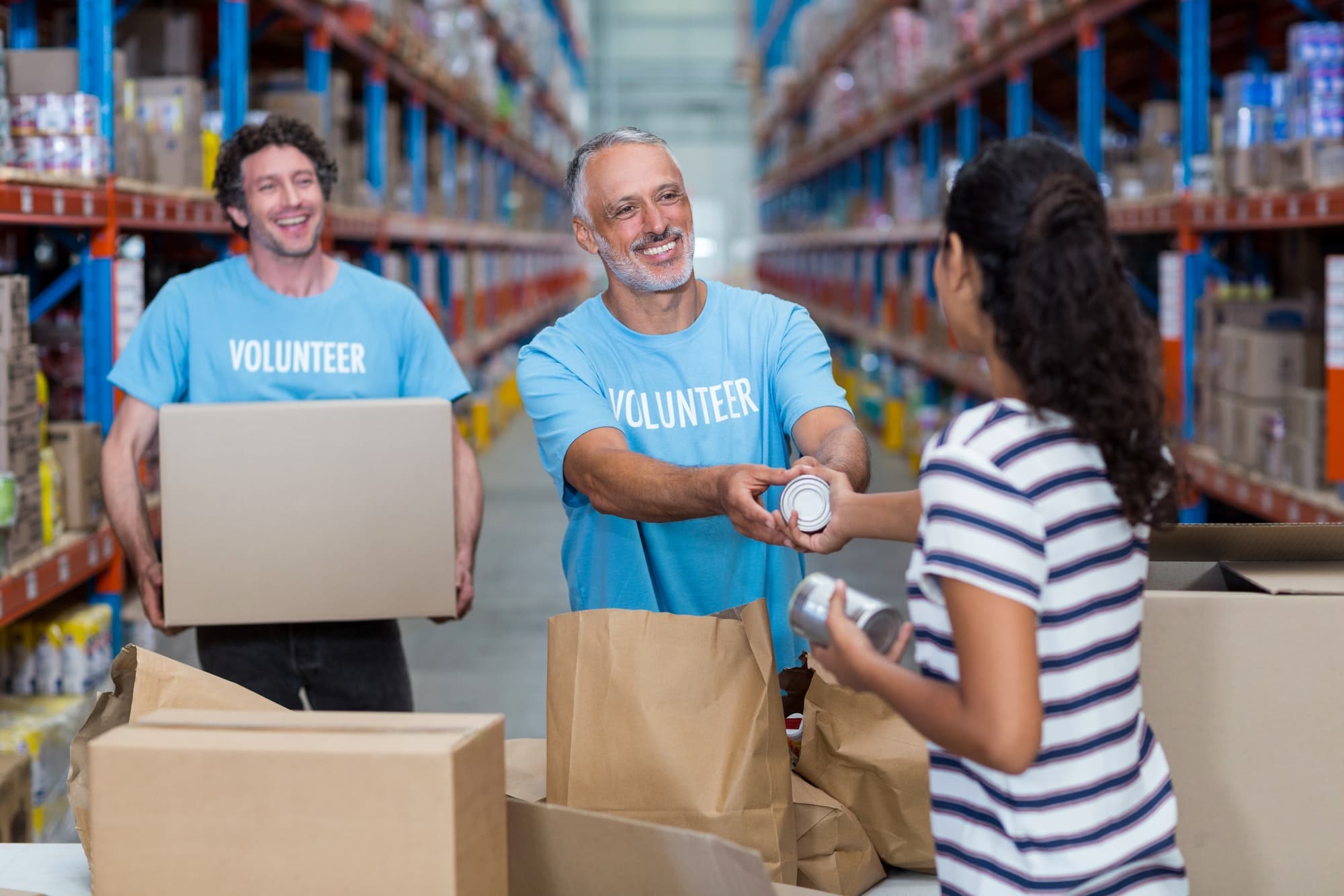Three volunteers packing eatables in cardboard box