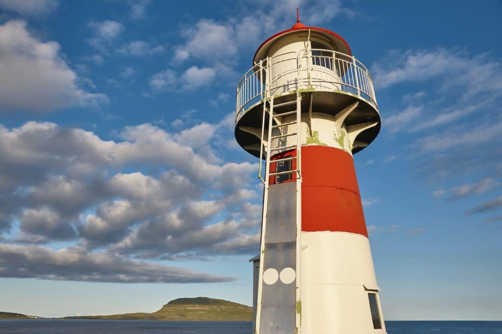 Red and white picturesque lighthouse in Faroe islands, Torshavn harbor